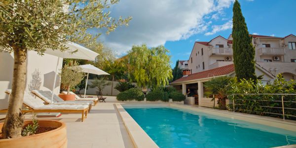 Curved swimming pool with rock features and artificial grass.