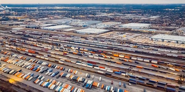 Aerial view of a vast freight train yard with numerous colorful containers and warehouses.