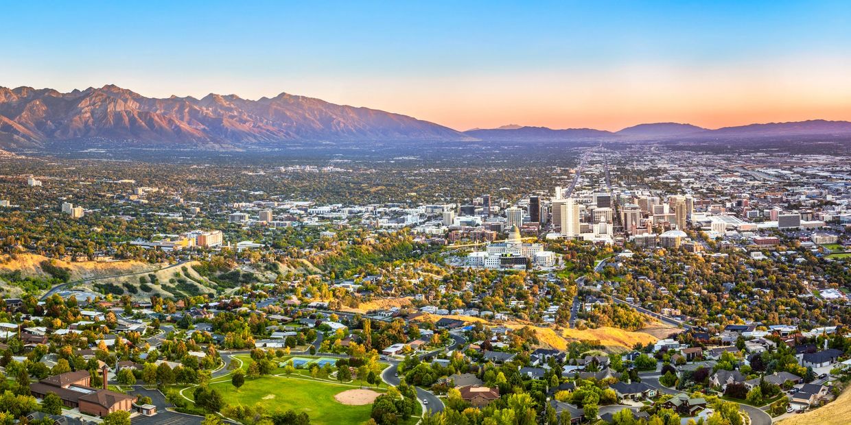 Panoramic view of a city with mountains in the background at sunset.