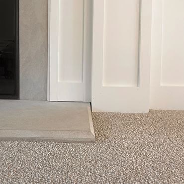 Close-up of a fireplace base with carpet and painted wall paneling.