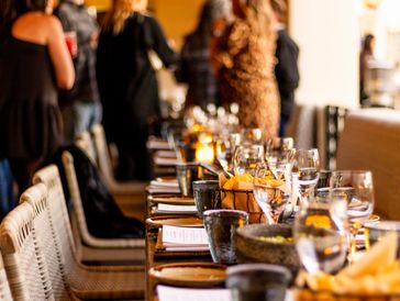 A long dining table set with glasses, plates, and food baskets, with people standing in the background.
Chef Esra Nur Büyük