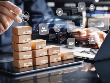 Stacked cardboard boxes with digital logistics icons and a laptop, symbolizing supply chain management.