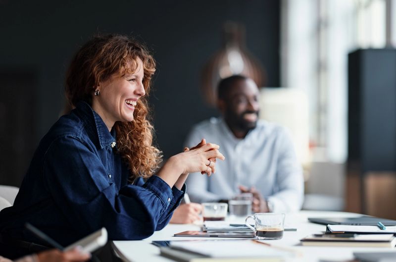 Professional team members discussing ideas during a business meeting in a bright workspace. Demonstrates collaboration, creativity, teamwork, and engagement, fostering a vibrant work environment to stimulate productivity and innovation.
