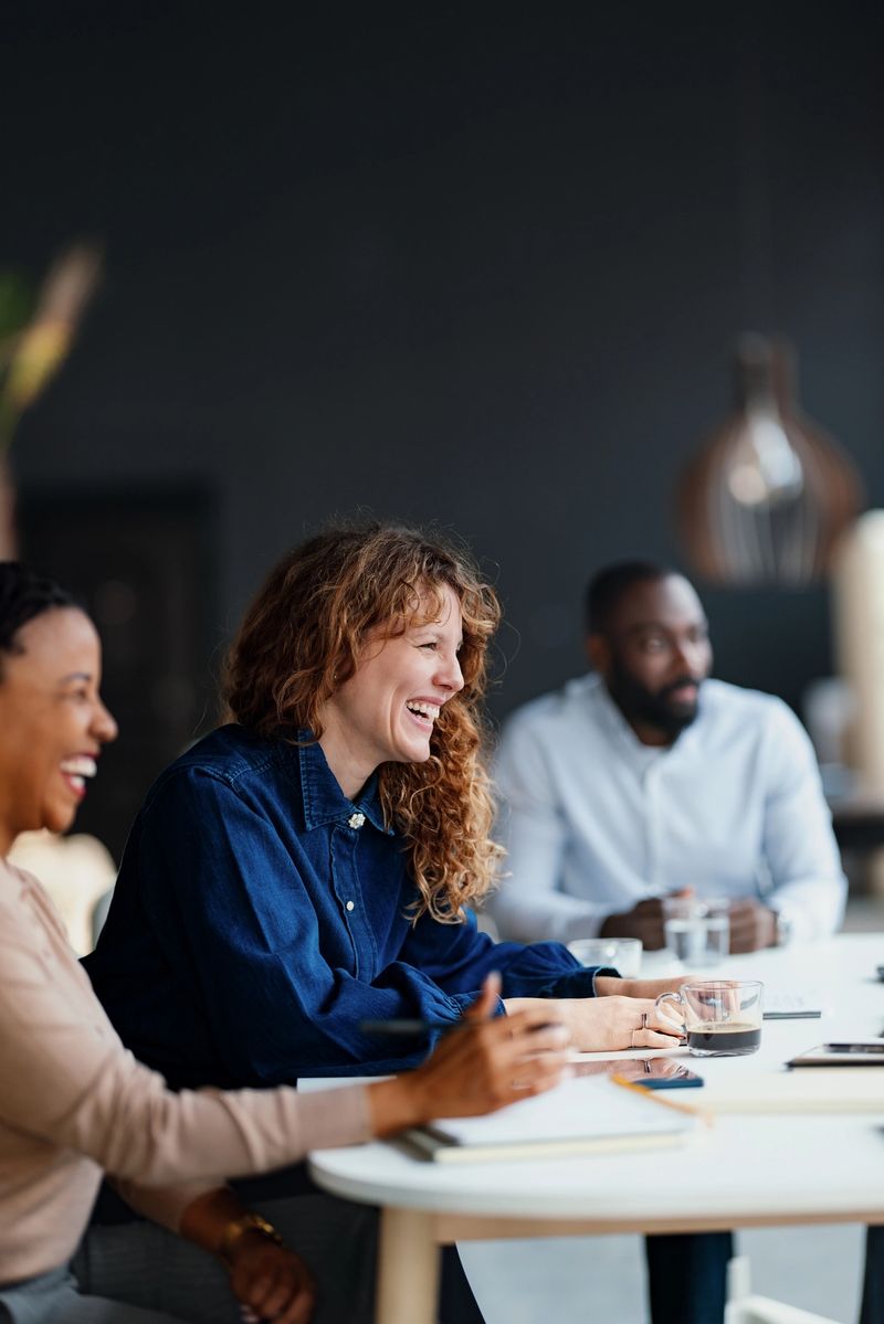 Three diverse professionals engaged in a lively discussion during a business meeting at a modern office.