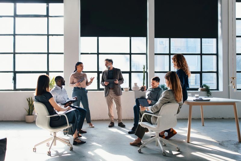 Group of professionals collaborating and discussing ideas in a bright contemporary office setting, showcasing teamwork and creativity.