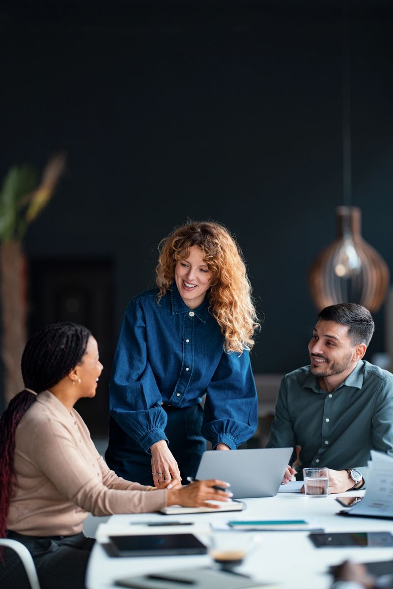 A diverse group of coworkers collaborate in a modern office, illustrating teamwork and productivity. The image depicts professional interaction, technology use, and a positive workplace atmosphere.