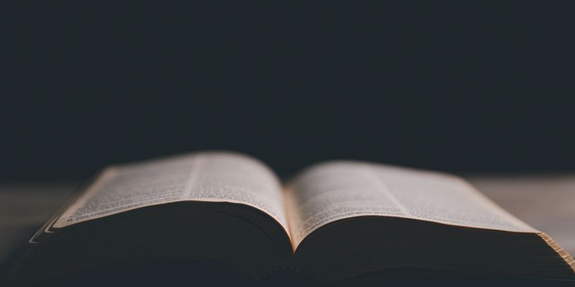 Open book with blurred text on dark background.