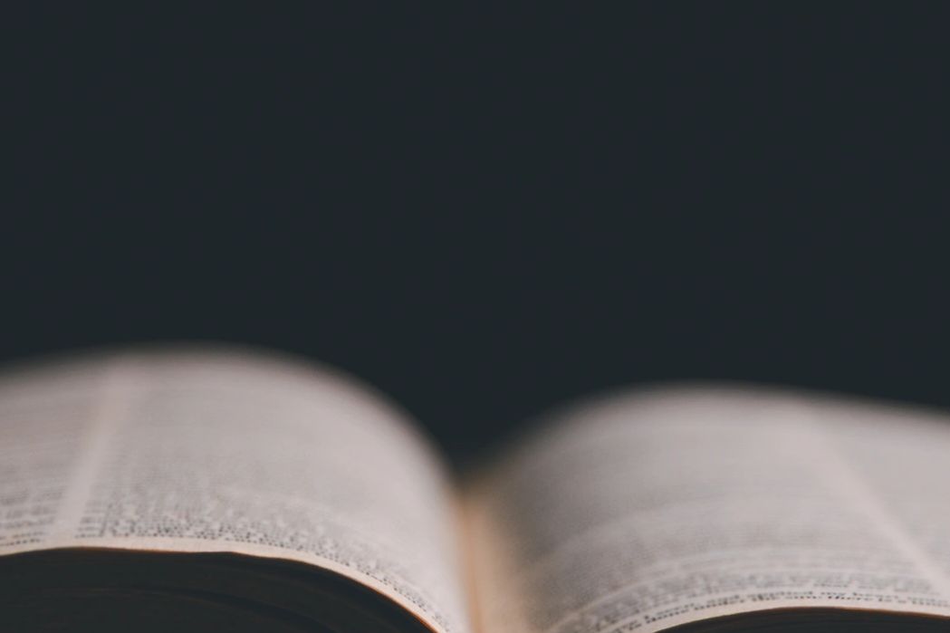 An open book lying on a wooden surface with a dark background.