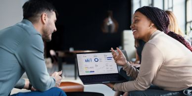 Two coworkers discussing data on a laptop.