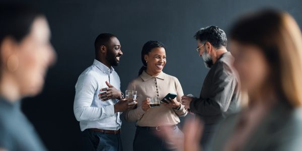 Three colleagues socializing at a work event with drinks.