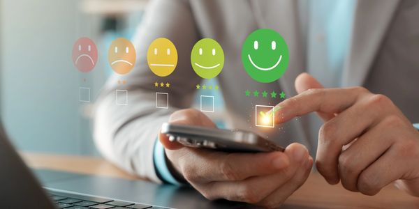 Person rating a service with a five-star happy face on a smartphone.