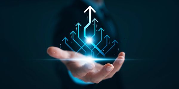 Hand holding glowing upward arrows symbolizing growth and innovation.