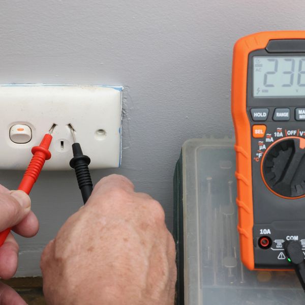 Measuring voltage of a power outlet with a digital multimeter.