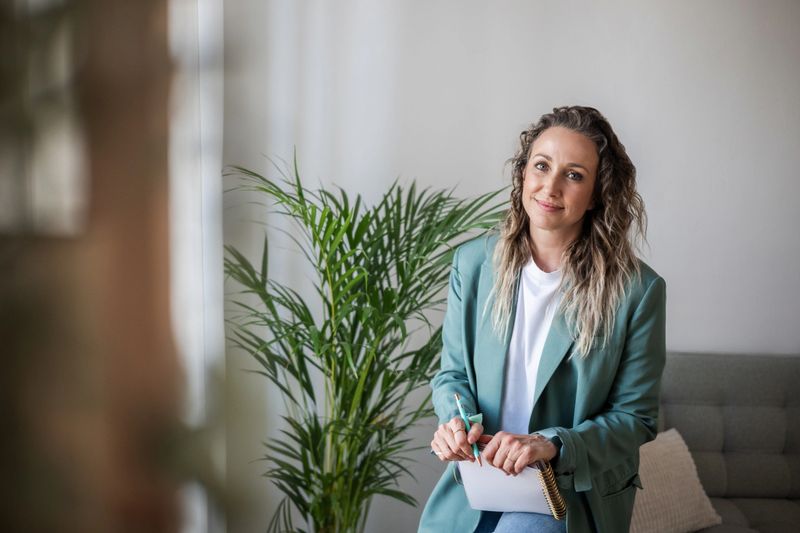 Female therapist smiling and taking notes during a therapy session in her home office