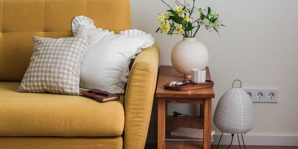 A yellow lounge with a side table against a wall