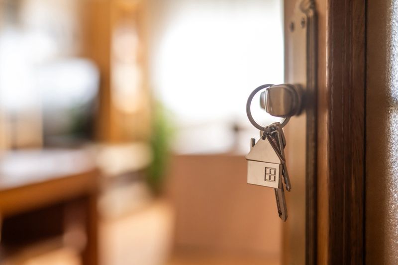 House-shaped keys are hanging from the door knob of a new home, representing the exciting moment of acquiring property and starting a fresh chapter