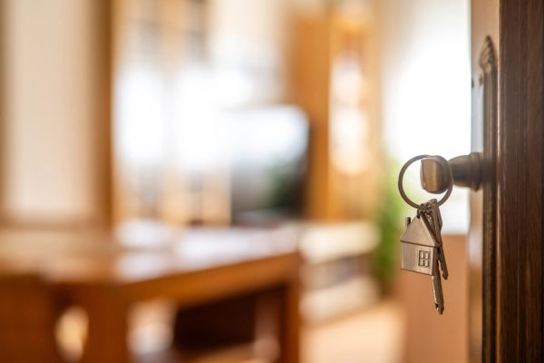 Key in door with house-shaped keychain.