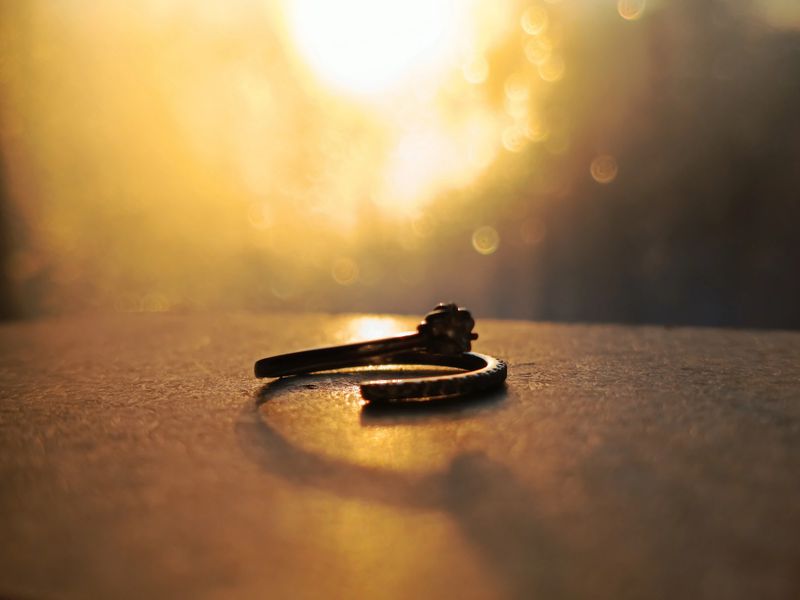 A ring with a precious stone on the table in the rays of the setting sun. The sun's rays shine on the silver ring. Engagement, wedding anniversary.