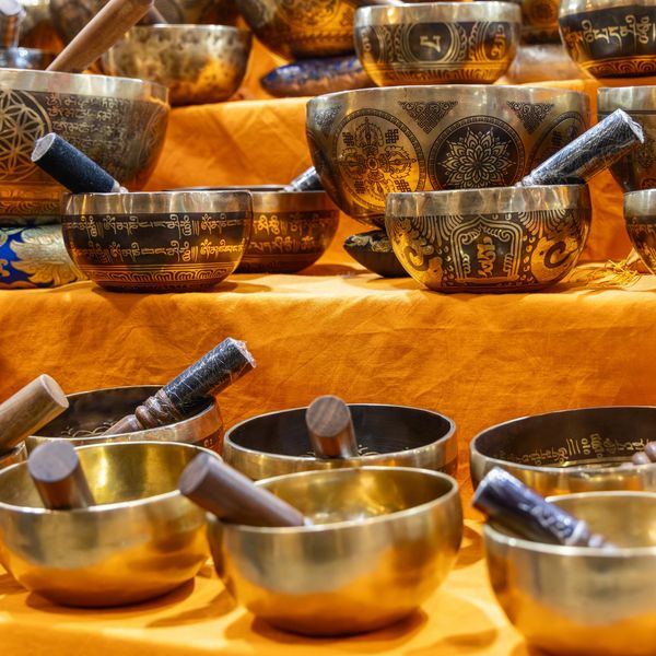 Decorative Tibetan singing bowls with wooden mallets on a vibrant yellow cloth.