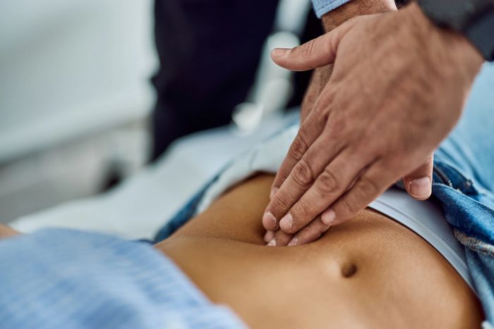 Close-up of a doctor examining a patient's abdomen with hands.