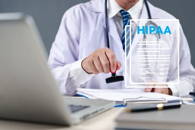 Doctor stamping a document labeled HIPAA in an office setting.