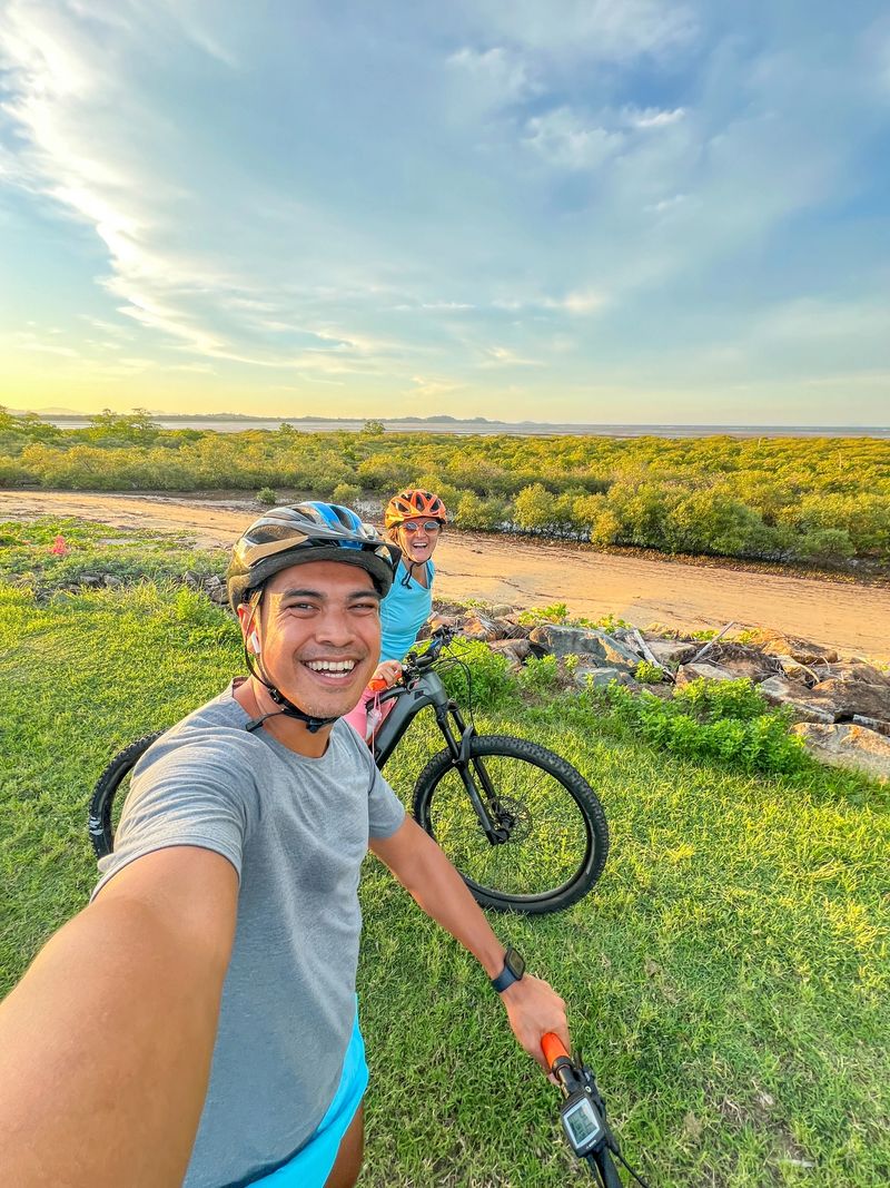 Smiling couple taking a break from biking in lush countryside. Happy cyclists capturing a moment in nature. Recreational activity promoting healthy lifestyle outdoors.