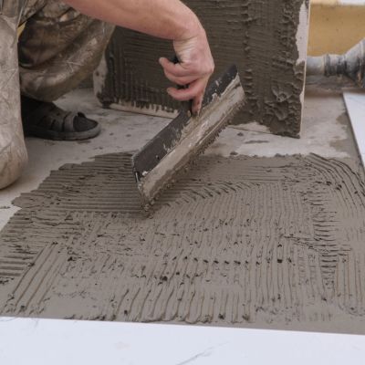 Person applying adhesive for tile installation.