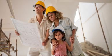 Family with hard hats reviewing blueprints at a construction site.