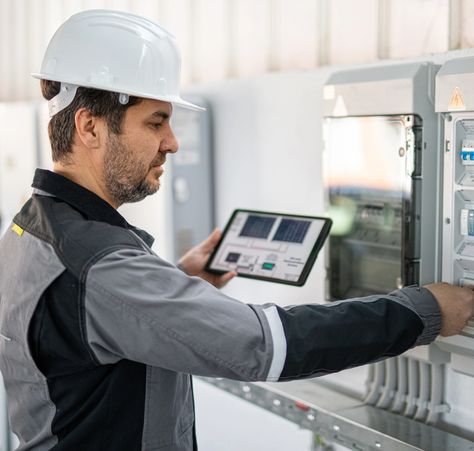 Engineer working on laptop with industrial equipment.