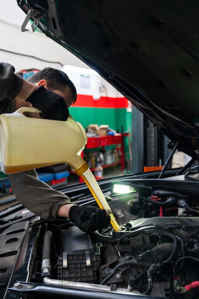 Serviceman checks the oil level in a car engine.