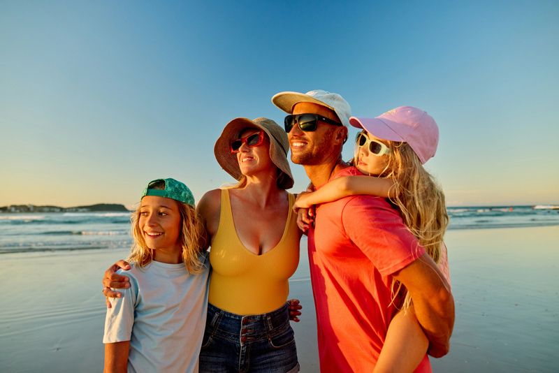 Happy family enjoying beach vacations in Australia at sunset
