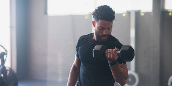 Man lifting a dumbbell during a workout in a gym.