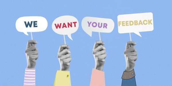 Hands hold signs saying We Want Your Feedback.
