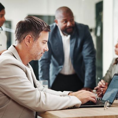Business professionals collaborating around a laptop in an office.