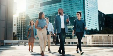 Diverse professionals walking and chatting outdoors in an urban setting.