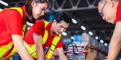 Three workers in safety vests collaborating over a project.
