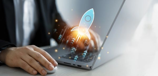 A person using a laptop with a digital rocket launch illustration.