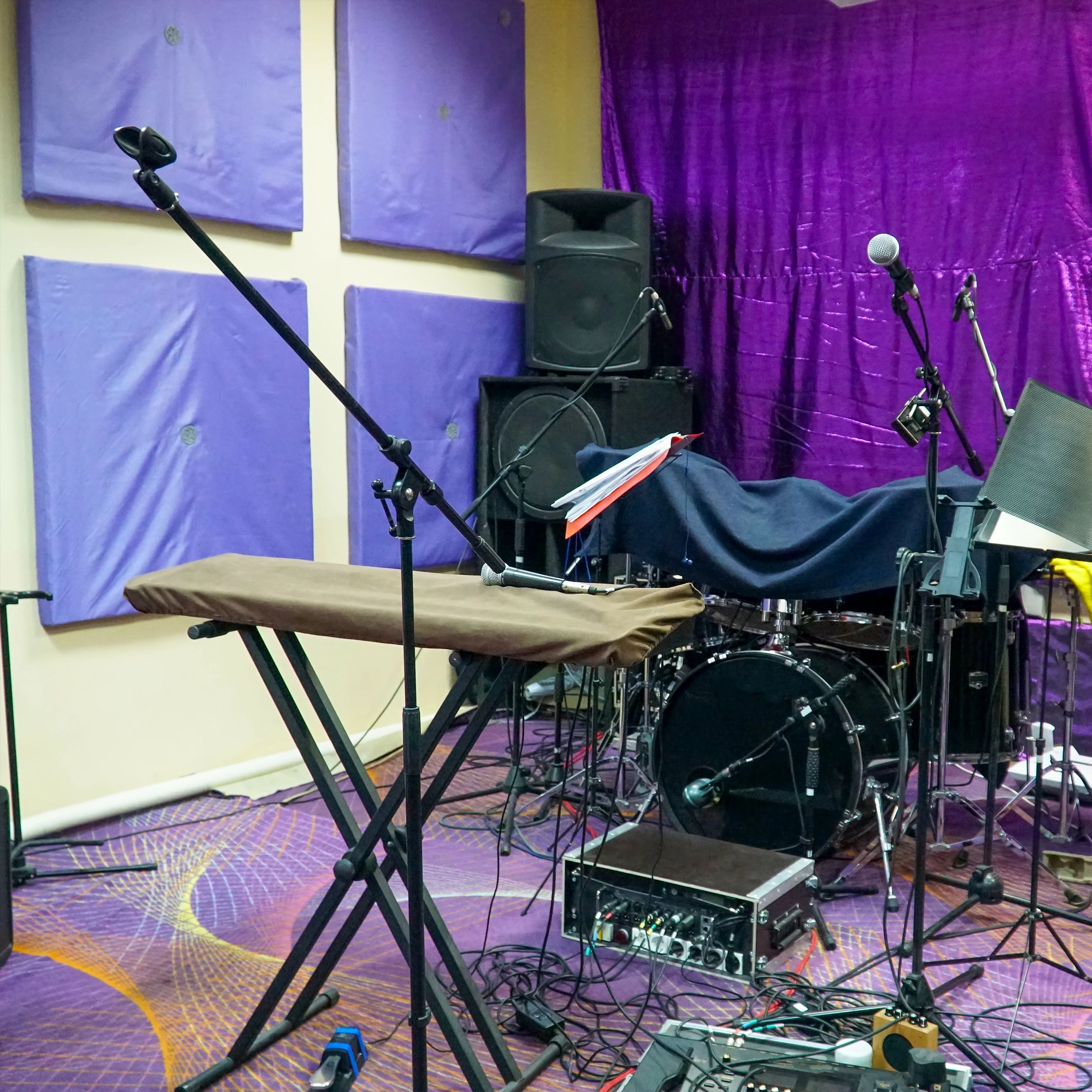 Music rehearsal room with microphones, speakers, and instruments.