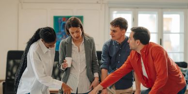 Four colleagues collaborating around a table in an office.