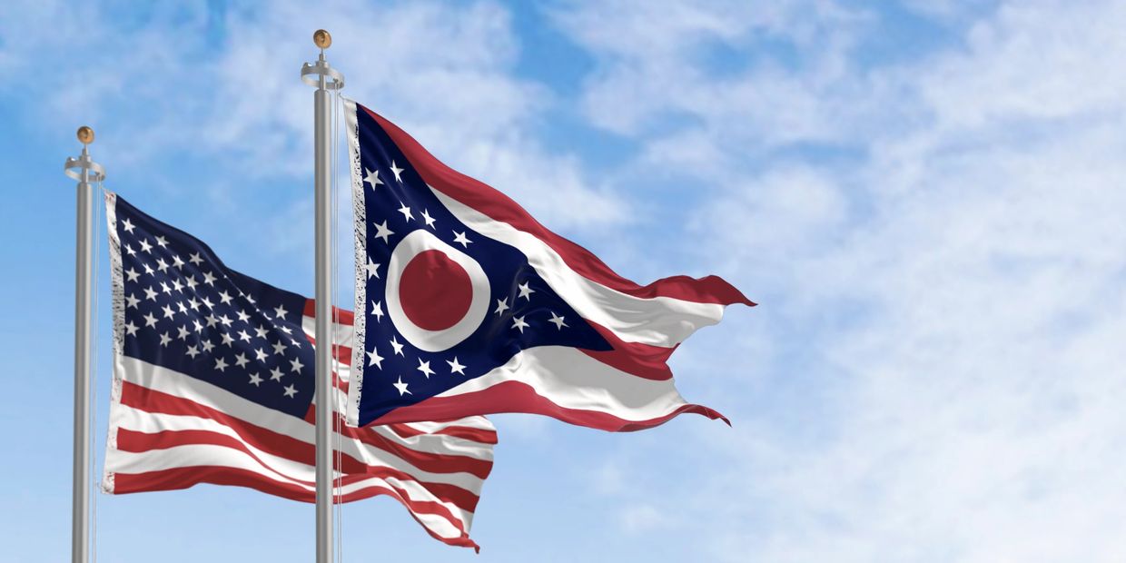 Two flags, American and Ohio state, waving in the wind.