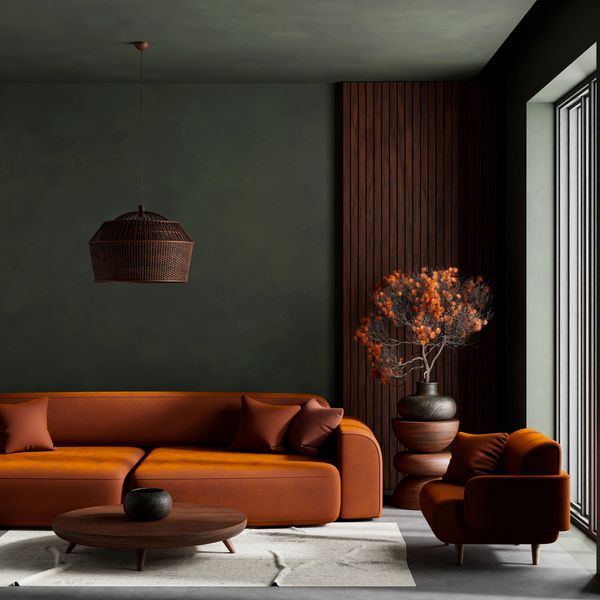 Modern living room with orange sofa, armchair, wooden accents, and dark green walls.