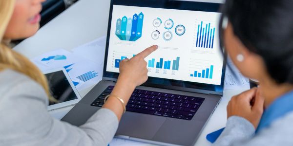 Two professionals analyzing data charts on a laptop in a meeting.
