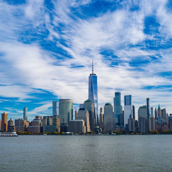 Skyline of New York City with One World Trade Center under a vivid blue sky.