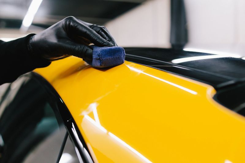 Process of applying a ceramic coating to the sports car surface for protection during detailing session at the service. Detailing ceramic polishing at the car service