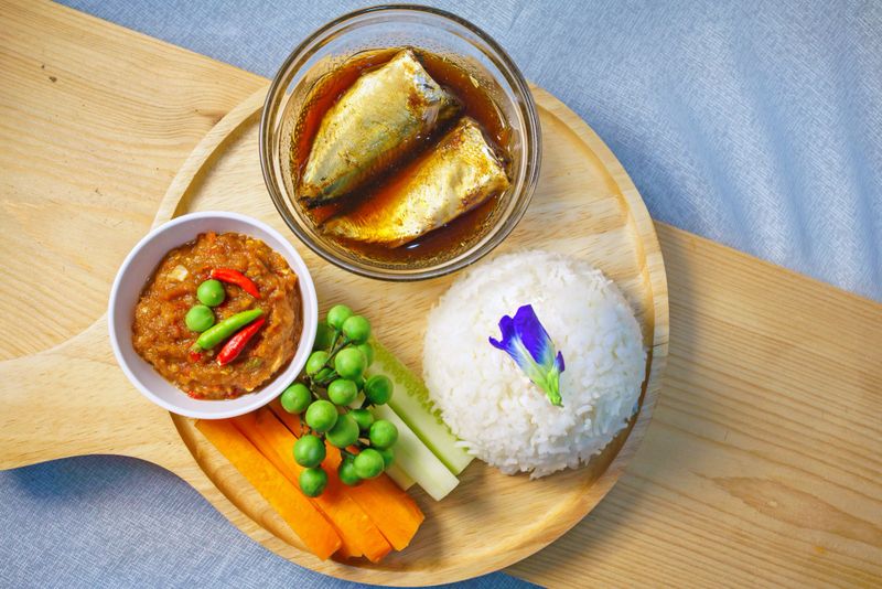 An appetizing arrangement of Thai cuisine featuring rice, fresh vegetables, and fish in sauce, highlighting vibrant colors and flavors for a wholesome meal.