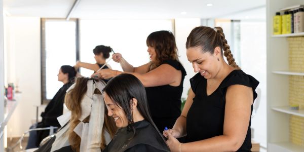 Hairstylists cutting and coloring hair in a salon.