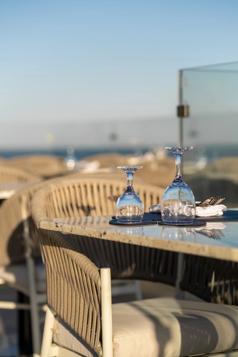 Sophisticated sunset dining setup at a seaside restaurant, complete with glassware and a scenic ocean view
