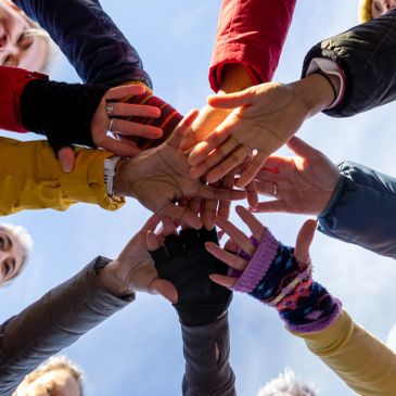 Group of people joining hands together in a circle.