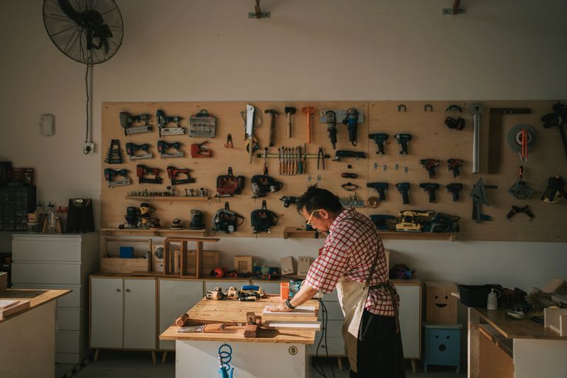 craftsmanship Asian chinese senior carpenter using sander polishing  piece of wood in woodshop