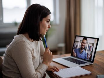 Woman attentively participating in a video call with a man on her laptop.